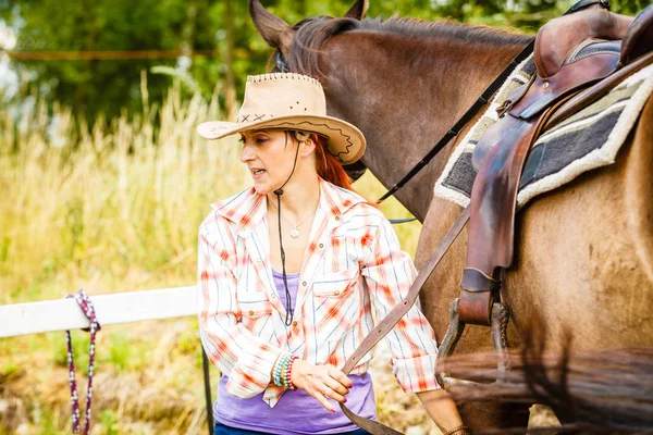 Cowgirl klaar paard voor rit op platteland — Stockfoto