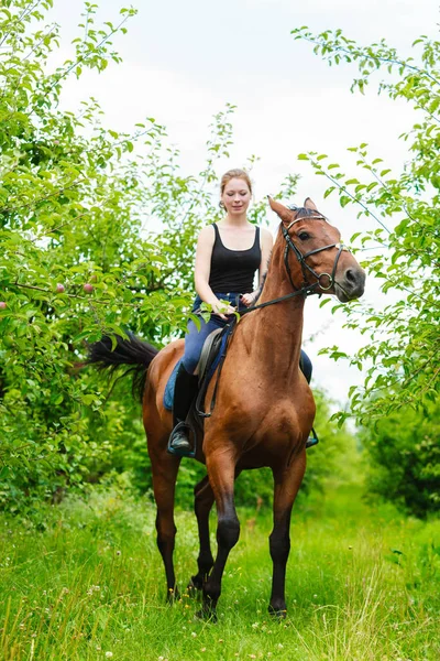 Jeune femme assise sur un cheval — Photo