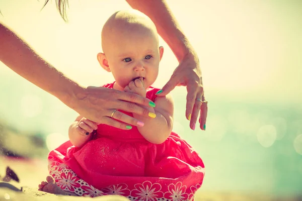 Babby umiejscowienia na piasku patrząc na ręce — Zdjęcie stockowe