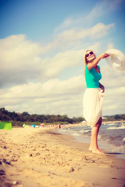 Donna sulla spiaggia gettando cappello da sole — Foto Stock