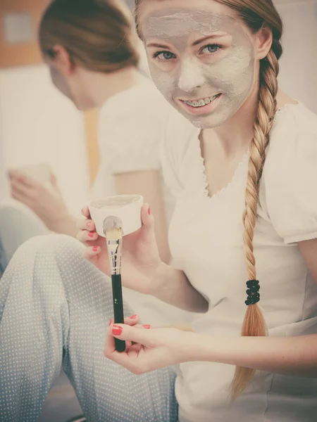 Happy young woman having mud mask on face — Stock Photo, Image