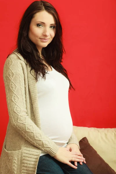 Sitting pregnant woman showing belly — Stock Photo, Image