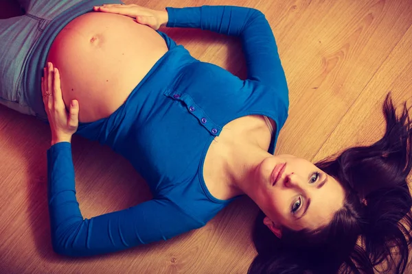 Žena ležela na podlaze ukazuje její těhotné břicho — Stock fotografie