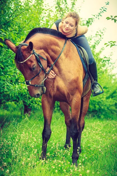 Молодая женщина обнимает и садится на лошадь — стоковое фото
