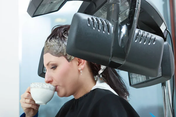 Kvinna i frisör, torkning håret under maskin — Stockfoto