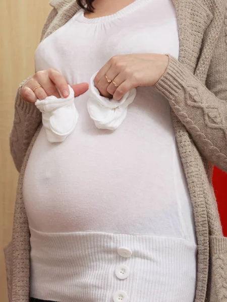 Pregnant woman holding little baby shoes — Stock Photo, Image