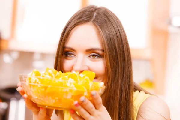 Woman holds bowl full of sliced orange fruits — Stock Photo, Image