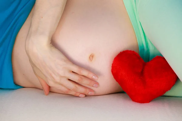 怀孕的女人躺在沙发上摸她的肚子上 — 图库照片