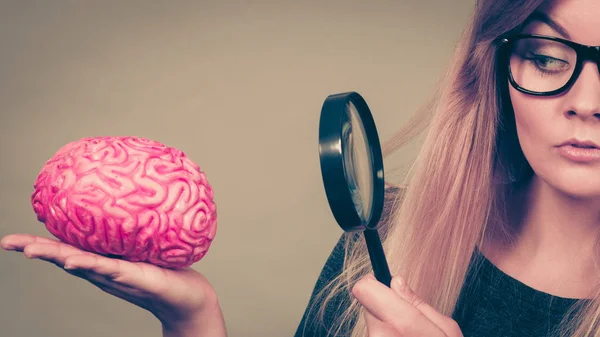 Женщина с увеличительным стеклом исследует мозг — стоковое фото