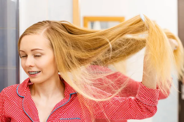 Mulher penteando seu cabelo comprido no banheiro — Fotografia de Stock