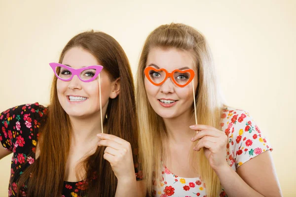 Twee gelukkige vrouwen houden van nep brillen op stick — Stockfoto