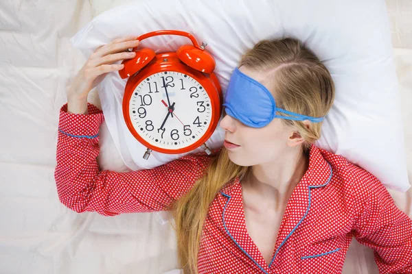 Schlafende Frau im Schlafanzug hält Uhr — Stockfoto
