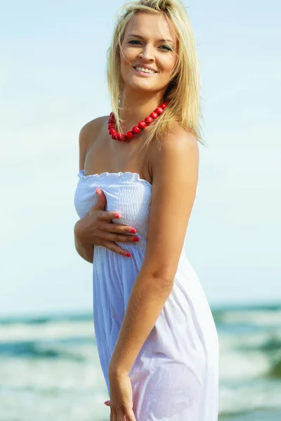 Blonde woman wearing dress walking in water — Stock Photo, Image