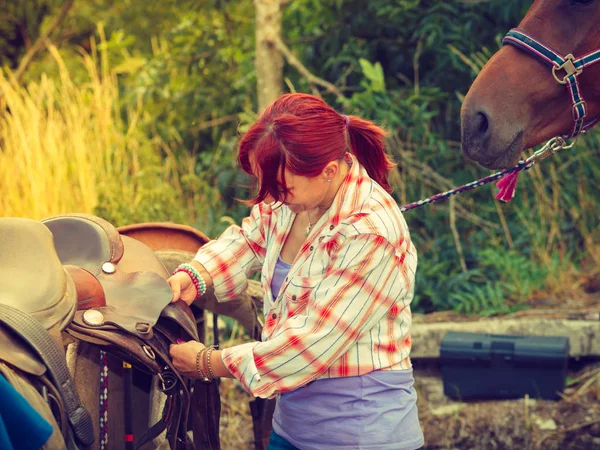 Vaquera conseguir caballo listo para montar en el campo — Foto de Stock