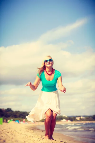 Donna bionda che indossa un vestito che gioca a saltare sulla spiaggia — Foto Stock