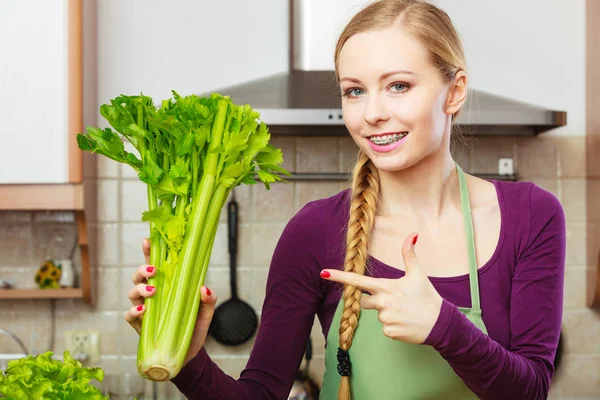 Femme dans la cuisine tient céleri vert — Photo