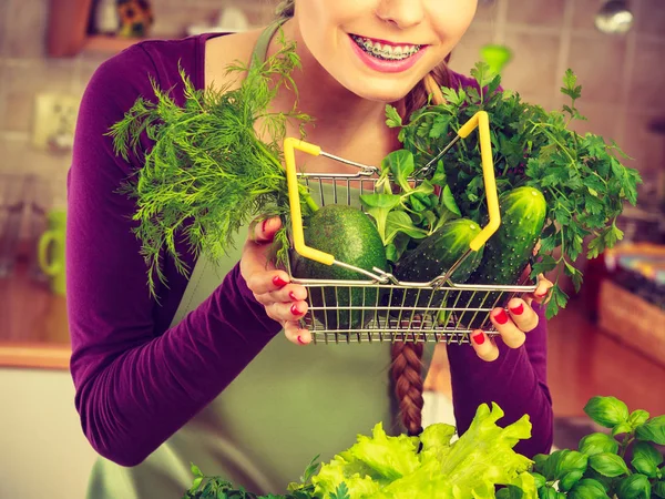 Mujer en cocina teniendo verduras sosteniendo cesta de la compra —  Fotos de Stock