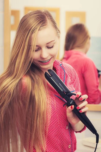 Donna raddrizzando i suoi lunghi capelli biondi — Foto Stock