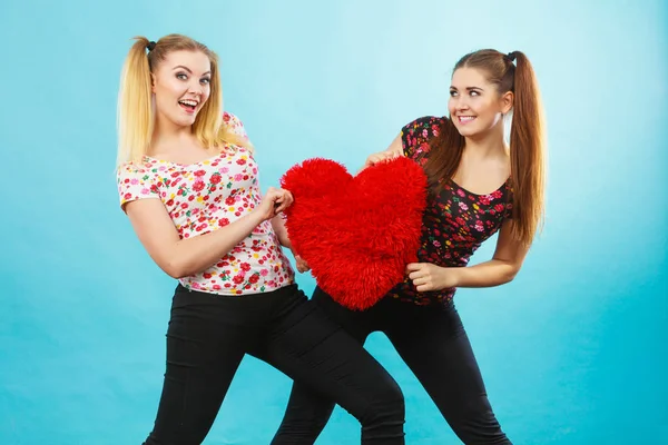 Feliz dos mujeres sosteniendo almohada en forma de corazón —  Fotos de Stock