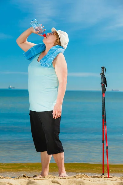 Senior woman practicing nordic walking on beach — Stock Photo, Image