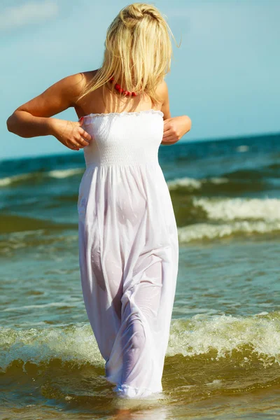 Blondine vrouw draagt jurk lopen in water — Stockfoto