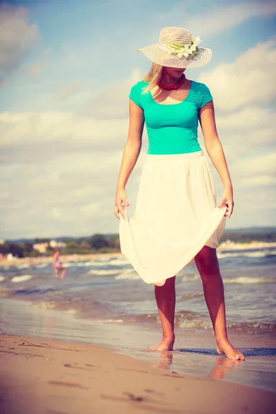 Blonde vrouw dragen jurk wandelen op strand — Stockfoto