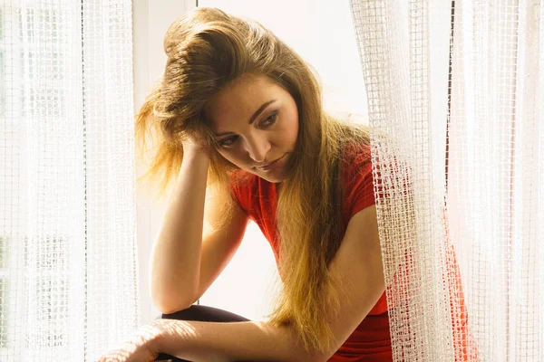 Mujer triste sentada en el alféizar de la ventana — Foto de Stock