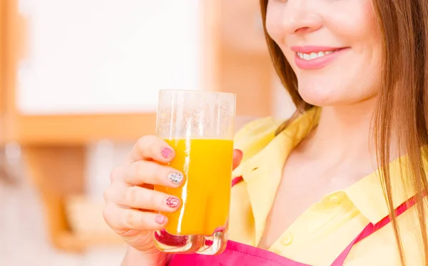 Жінка на кухні п'є свіжий апельсиновий сік — стокове фото