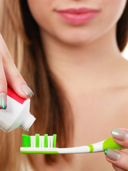 Woman applying toothpaste on her toothbrush — Stock Photo, Image