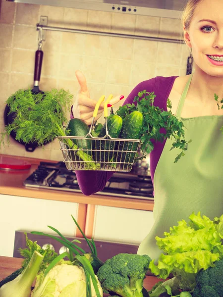 Kvinna i köket med grönsaker håller varukorg — Stockfoto