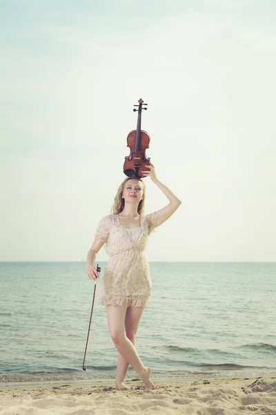 Femme sur la plage près de la mer tenant violon — Photo