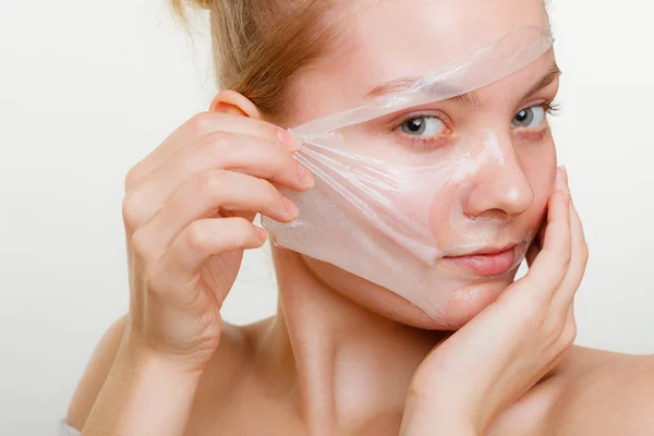 Kvinna att ta bort facial peel off mask. — Stockfoto