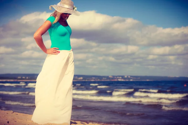 Femme blonde portant une robe marchant sur la plage — Photo