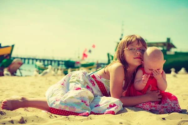 Toddler dziewczynka tulenie młodsza siostra na plaży. — Zdjęcie stockowe