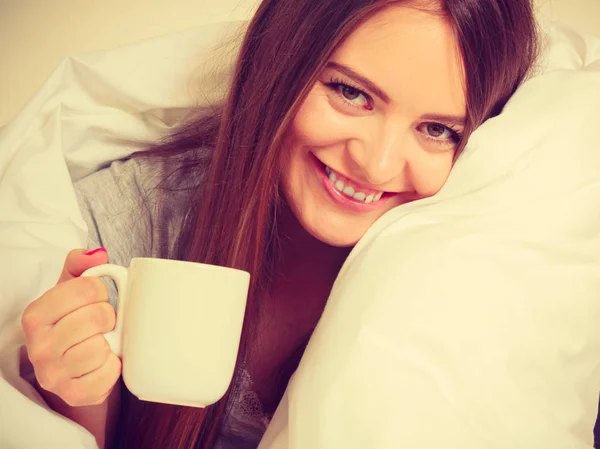 Sorrindo mulher segurando copo de bebida na cama — Fotografia de Stock