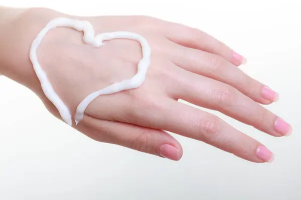 Crema sulla mano della donna, forma di cuore — Foto Stock