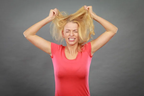 Frustrated woman holding her damaged blonde hair Royalty Free Stock Photos