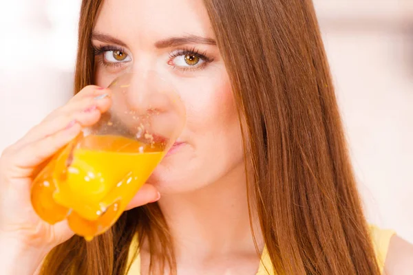 Kvinnan i köket dricka färskpressad apelsinjuice — Stockfoto