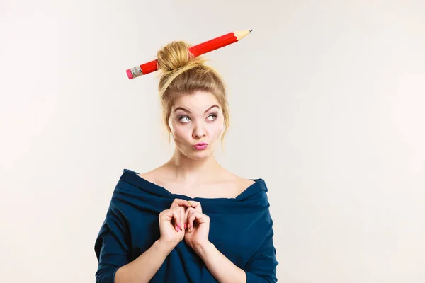 Tänkande blond kvinna med stora penna i hår — Stockfoto