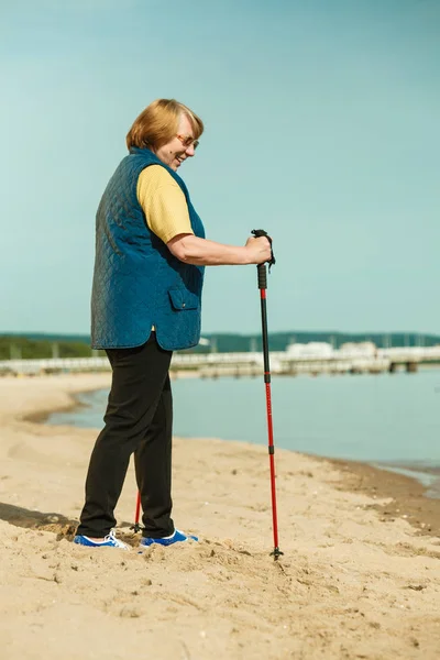Seniorin übt Nordic Walking am Strand — Stockfoto