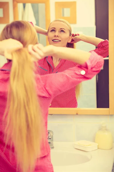 Mulher penteando seu cabelo comprido no banheiro — Fotografia de Stock