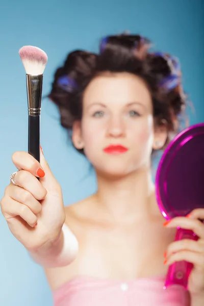 Kobieta w wałki do włosów utrzymuje makijaż szczotka — Zdjęcie stockowe