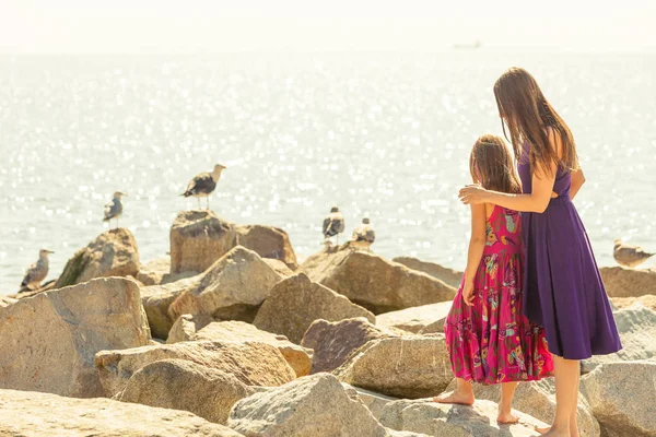 Mor och dotter tittar seagulls nära havet — Stockfoto