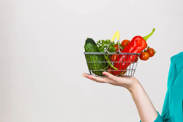 Mulher mão segura cesta de compras com legumes — Fotografia de Stock