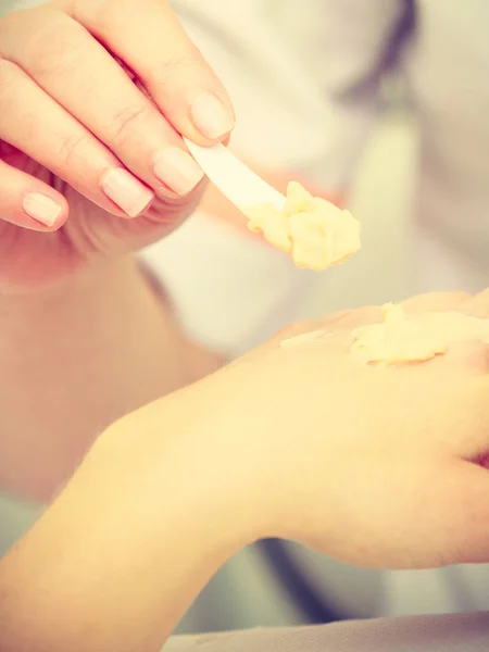 Mujer aplicando crema en la mano usando espátula — Foto de Stock