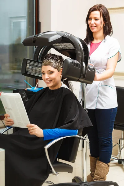 Donna in parrucchiere, asciugatura capelli sotto macchina — Foto Stock