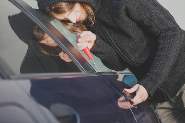 Thieft człowiek trzyma śrubokręt włamaniu do samochodu — Zdjęcie stockowe