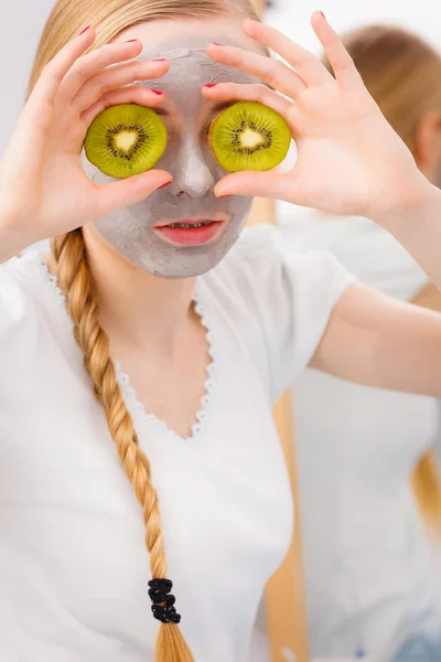 Jovem feliz tendo máscara facial segurando kiwi — Fotografia de Stock