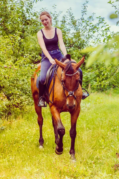 Ung kvinna sitter på en häst — Stockfoto