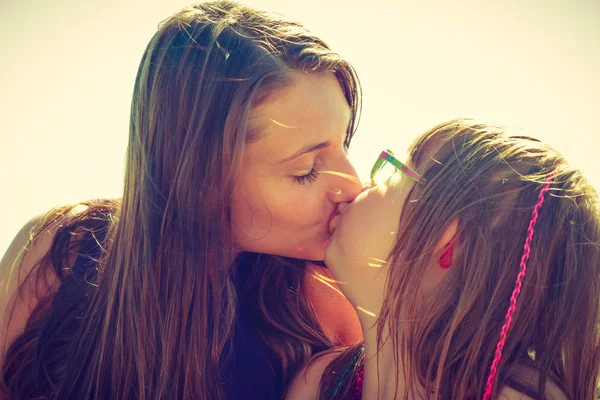 Vrouw en meisje kussen in de buurt van zee-rotsen — Stockfoto